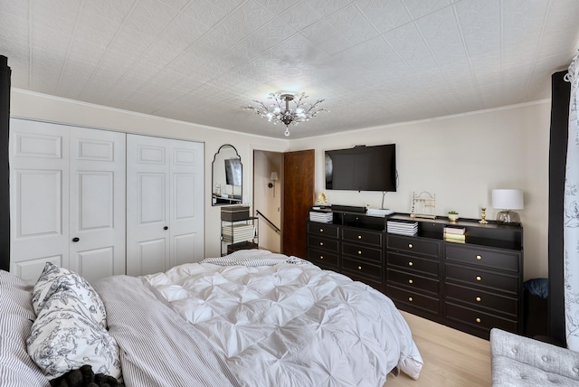 bedroom featuring crown molding, light wood-style flooring, a closet, and a chandelier