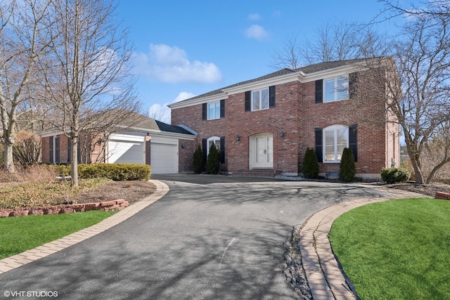 colonial home with brick siding, driveway, and an attached garage