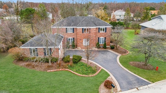 view of front of property featuring a front yard, brick siding, and driveway