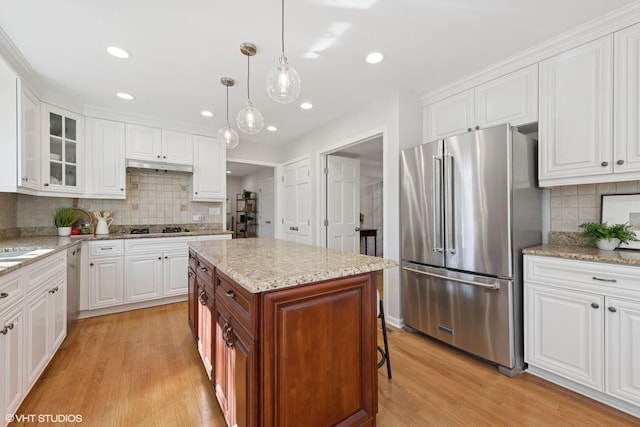 kitchen with appliances with stainless steel finishes, white cabinets, and light wood finished floors