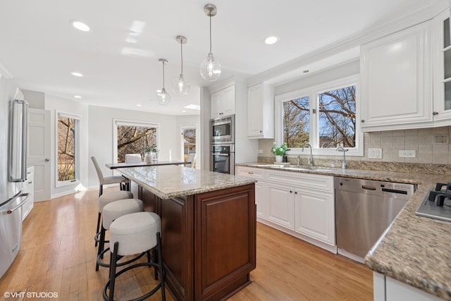 kitchen with backsplash, stainless steel appliances, light wood-style floors, and a center island