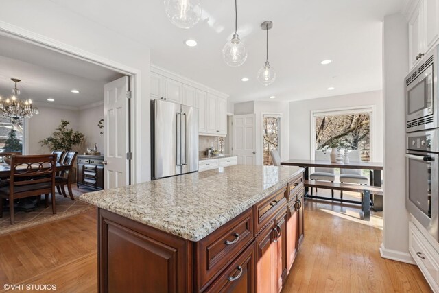 kitchen featuring white cabinets, light stone countertops, light wood finished floors, and stainless steel appliances