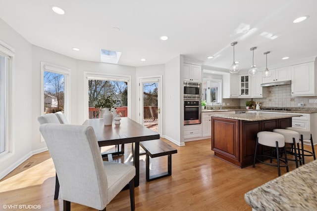 kitchen featuring decorative backsplash, appliances with stainless steel finishes, light wood-style flooring, and white cabinetry