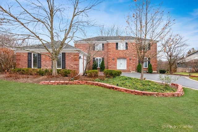 view of front of house featuring aphalt driveway, a garage, brick siding, and a front yard