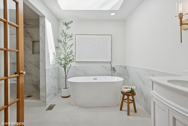 bathroom featuring a marble finish shower, visible vents, a skylight, a freestanding tub, and vanity