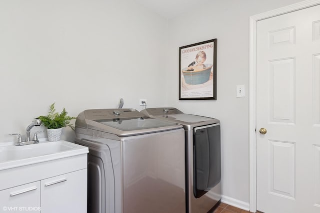 laundry room featuring baseboards, cabinet space, a sink, washer and dryer, and dark tile patterned floors