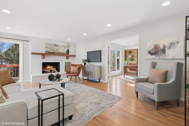 living area featuring a brick fireplace, recessed lighting, light wood-style floors, and baseboards