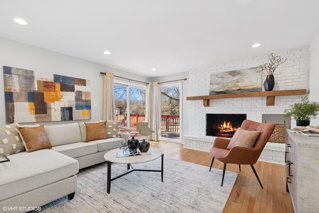 living area featuring recessed lighting, light wood-style flooring, and a fireplace