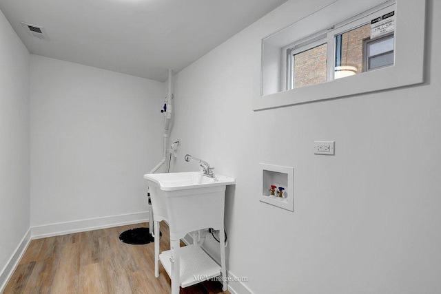 clothes washing area featuring hookup for a washing machine, visible vents, wood finished floors, laundry area, and baseboards