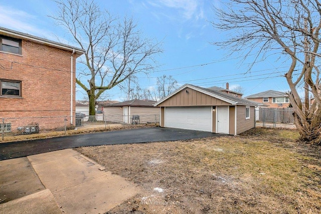 view of side of home with a garage, fence, board and batten siding, and an outdoor structure