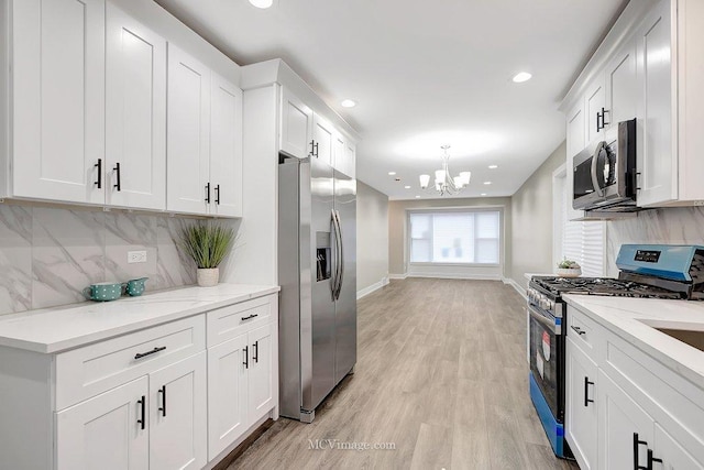 kitchen with stainless steel appliances, baseboards, white cabinets, decorative backsplash, and light wood finished floors