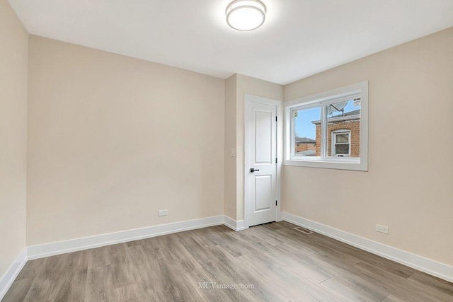 empty room with visible vents, baseboards, and wood finished floors