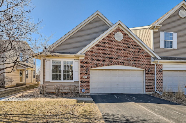 view of front of house featuring a garage, aphalt driveway, and brick siding