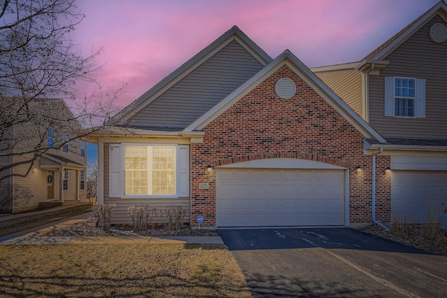 traditional-style home featuring brick siding, driveway, and an attached garage