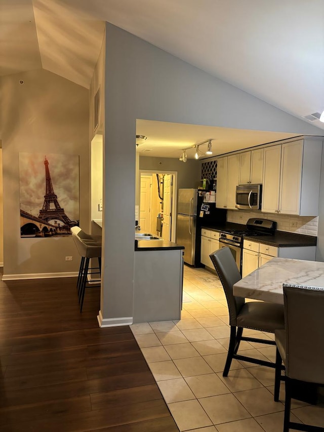 kitchen with stainless steel appliances, lofted ceiling, light wood-type flooring, and visible vents