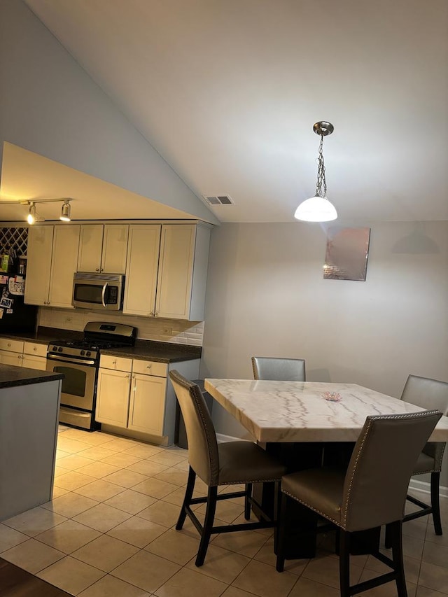 dining room with vaulted ceiling, light tile patterned floors, and visible vents