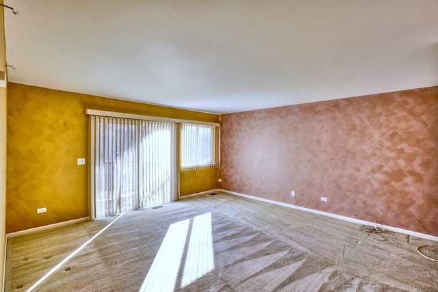 spare room with baseboards and carpet flooring