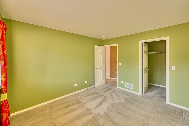 unfurnished bedroom featuring a spacious closet, visible vents, and baseboards