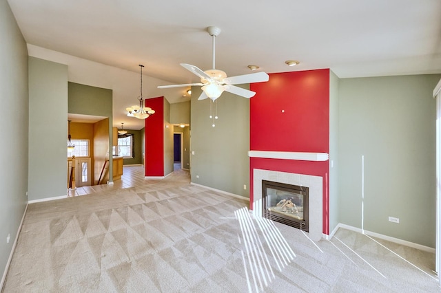 unfurnished living room featuring ceiling fan with notable chandelier, a fireplace, baseboards, and carpet floors