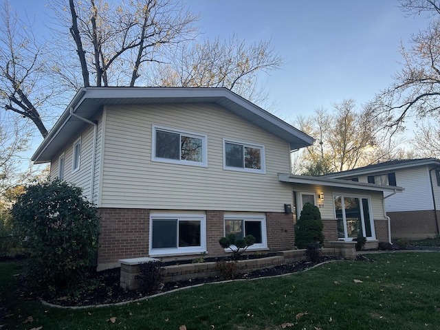 tri-level home featuring brick siding and a front lawn