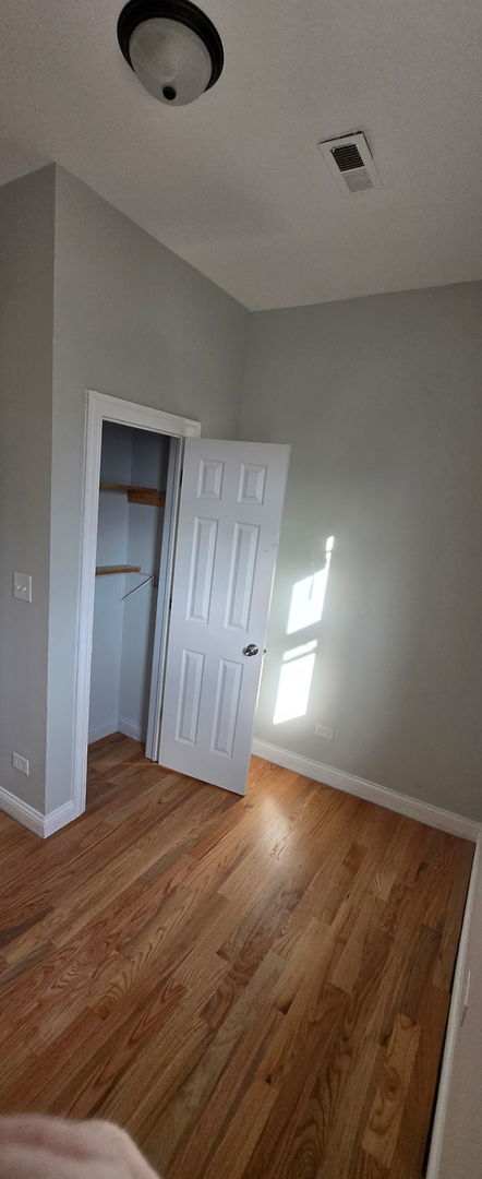 unfurnished bedroom with baseboards, a closet, visible vents, and wood finished floors