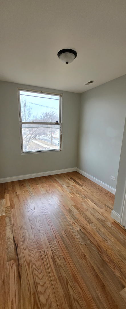 empty room with light wood-style floors, visible vents, and baseboards