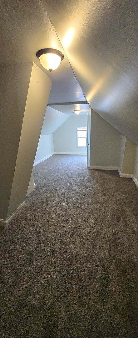 bonus room featuring carpet floors, vaulted ceiling, a textured ceiling, and baseboards