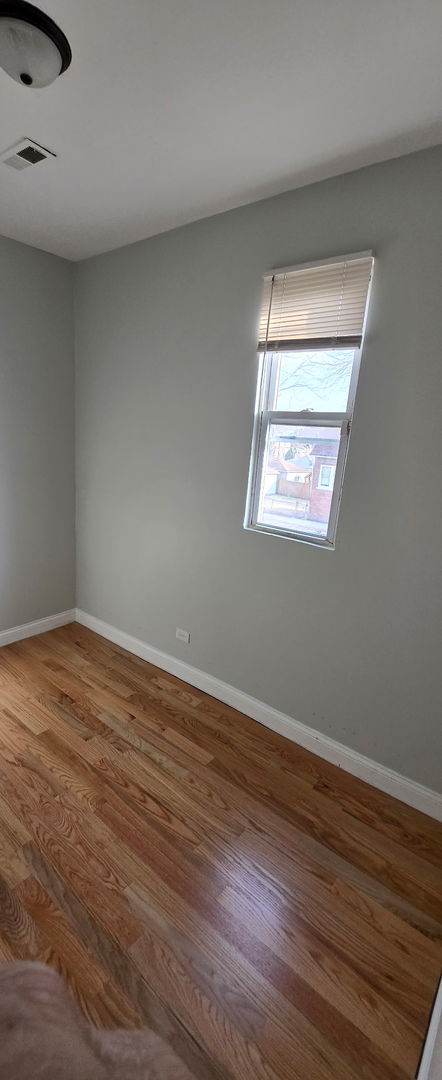 spare room with visible vents, baseboards, and wood finished floors