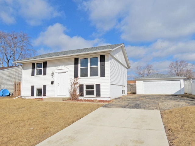 bi-level home featuring a garage, a front yard, fence, and an outbuilding