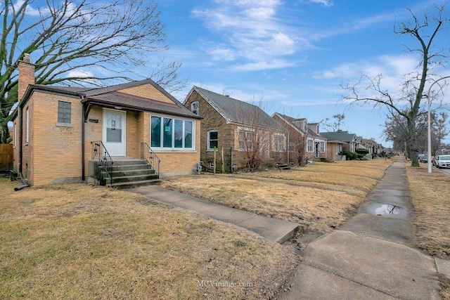 view of front of home with brick siding, a chimney, and a front yard