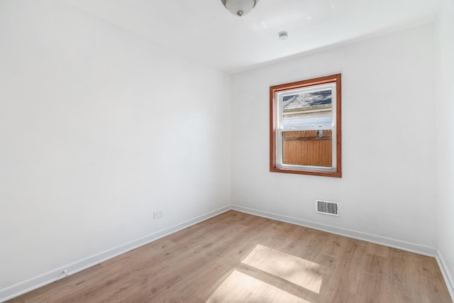 empty room with baseboards, visible vents, and light wood finished floors