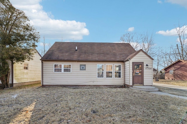 back of property featuring a yard and a shingled roof