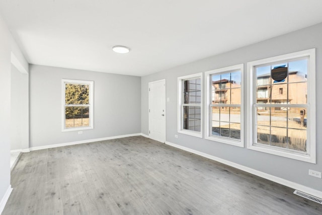 unfurnished room featuring wood finished floors, visible vents, and baseboards