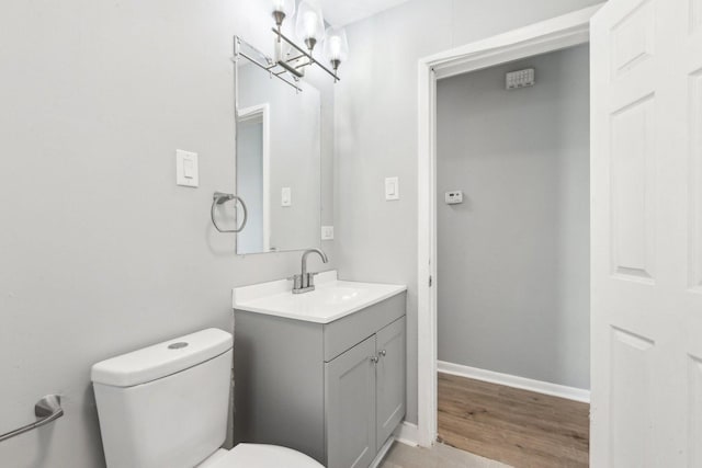 bathroom featuring wood finished floors, vanity, toilet, and baseboards