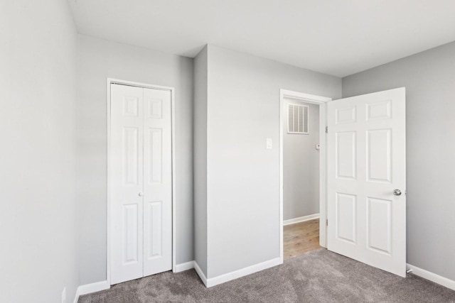 unfurnished bedroom featuring carpet, visible vents, baseboards, and a closet