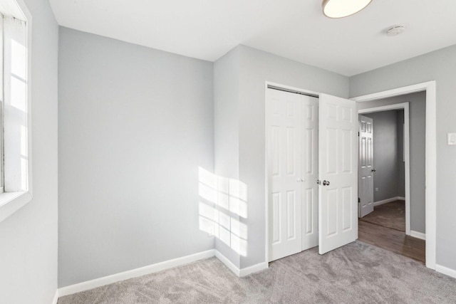 unfurnished bedroom featuring carpet floors, multiple windows, baseboards, and a closet