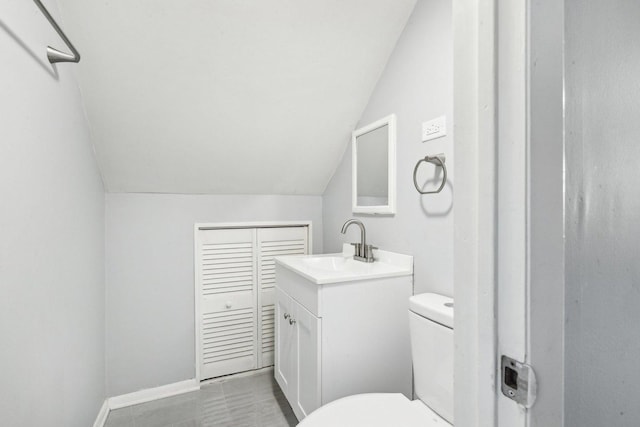 bathroom featuring toilet, baseboards, lofted ceiling, and vanity