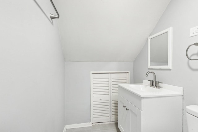 bathroom with lofted ceiling, baseboards, toilet, and vanity