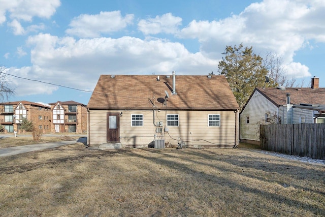 rear view of property with entry steps, a lawn, fence, and cooling unit