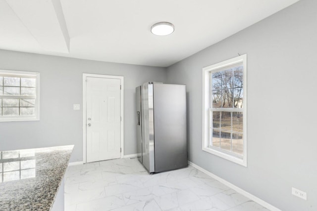 interior space with marble finish floor, multiple windows, freestanding refrigerator, and baseboards