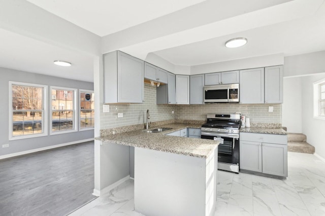 kitchen featuring gray cabinetry, a sink, baseboards, marble finish floor, and gas range