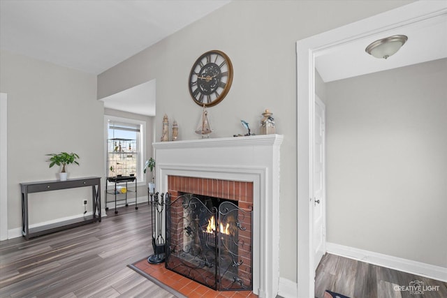 living room with a brick fireplace, baseboards, and wood finished floors