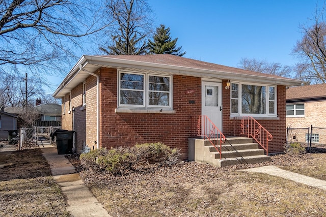 bungalow featuring a gate, brick siding, and fence