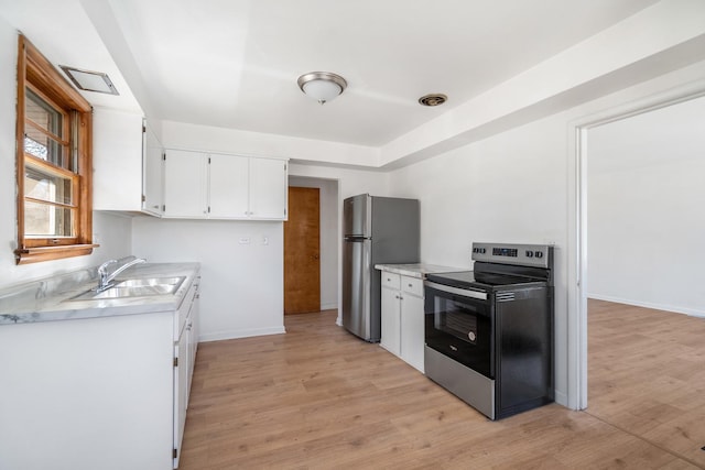 kitchen with stainless steel appliances, light countertops, light wood-style floors, white cabinetry, and a sink