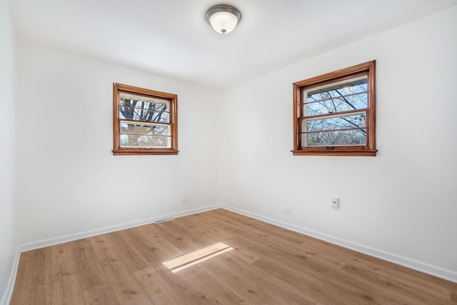 empty room featuring baseboards, light wood-type flooring, and a healthy amount of sunlight