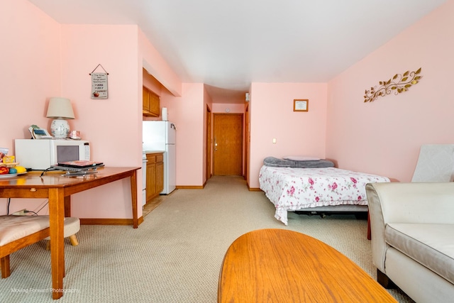 bedroom featuring baseboards, freestanding refrigerator, and light colored carpet