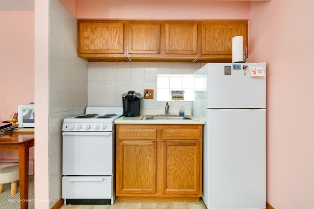 kitchen featuring white appliances, a sink, light countertops, backsplash, and brown cabinets