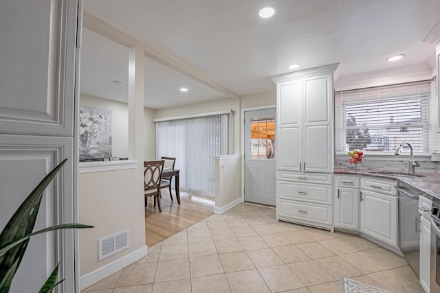 kitchen featuring light tile patterned floors, visible vents, white cabinetry, a sink, and dishwasher