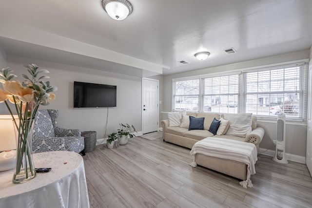 living area featuring visible vents, light wood finished floors, and baseboards