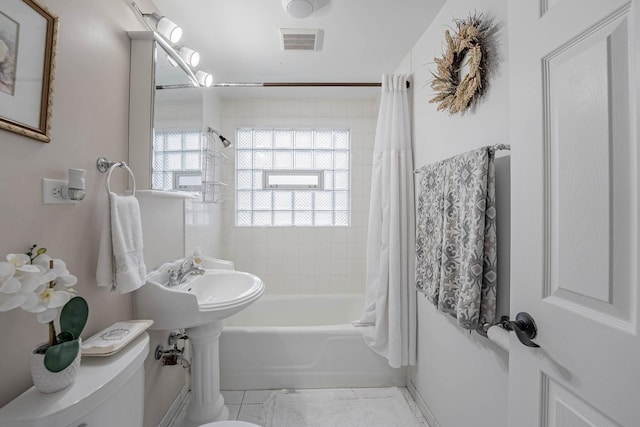 full bathroom featuring toilet, visible vents, and shower / bathtub combination with curtain